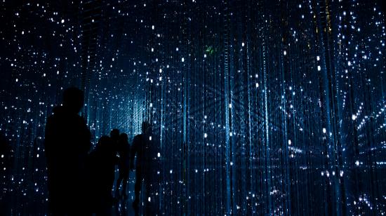 Dark room with rays of blue light. Robynne/Unsplash