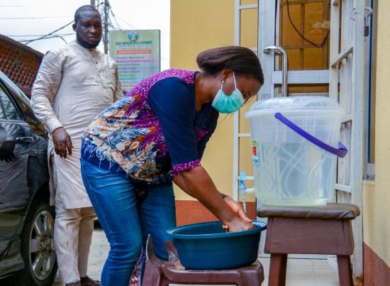 A woman washes her hands at a makeshift hand-washing system in Lagos Nigeria, Credit: Oluwafemi Dawodu/Shutterstock