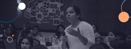A woman at a meeting standing holding a microphone